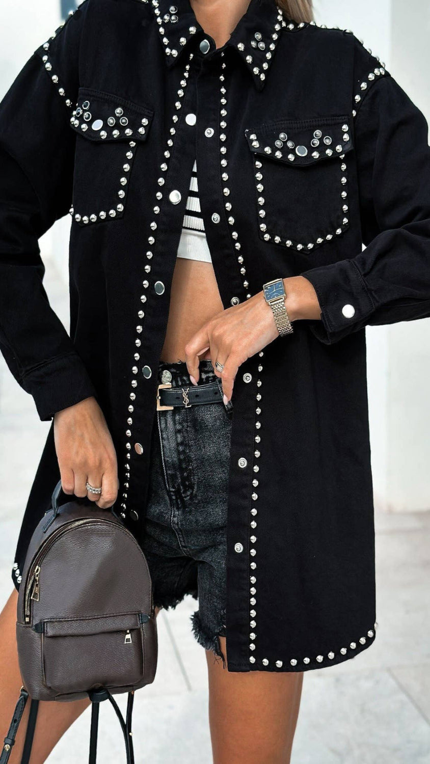 Person wearing a black studded jacket with a blurred background