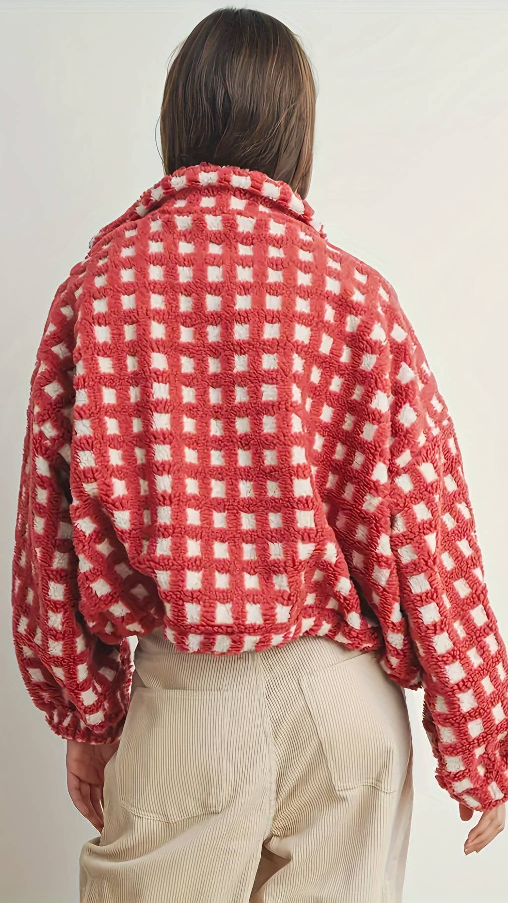 Person wearing a red and white checkered jacket on a plain background